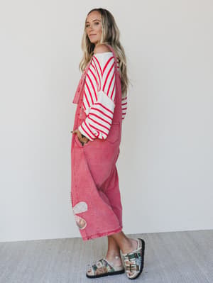 Woman wearing a red and white striped sweater and pink pants with a white background