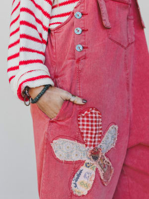 Red denim jacket with floral patch on a plain background