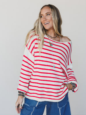 Woman wearing a red and white striped sweater with a plain background