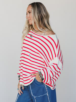 Woman wearing a red and white striped sweater with blue jeans on a plain background