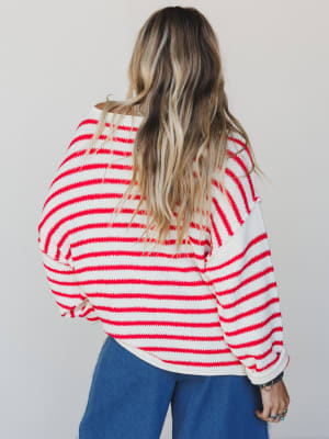 Person wearing a red and white striped sweater with a plain background
