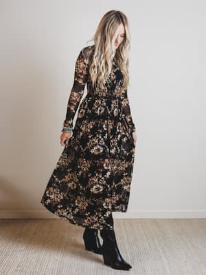 Woman wearing a long floral dress against a plain background