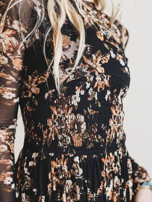 Close-up of a person wearing a floral dress with a neutral background