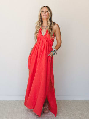 A flowy cherry red halter maxi dress in crinkle gauze fabric styled with stacked beaded bracelets and a layered necklace — effortless and warm, like the best day of summer.