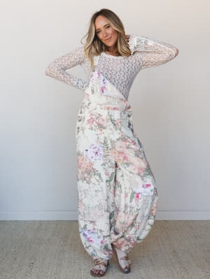 A wide-leg floral overall layered over a sheer lace long-sleeve top — the kind of outfit that feels like wandering through a garden without trying too hard.