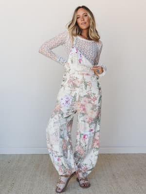 A wide-leg floral overall paired with a sheer lace long-sleeve top — the kind of outfit that looks like it was pulled from a garden party dream and somehow works for Tuesday.