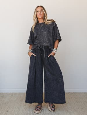 A matching acid-wash charcoal two-piece set — oversized tee and wide-leg drawstring pants — styled with platform sandals and stacked turquoise bracelets for an effortlessly relaxed, boho-cool look.