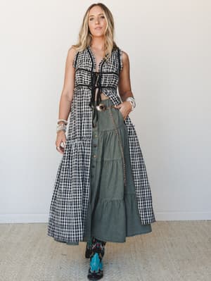 A layered three-piece set styled with effortless western boho energy — a gingham crop top and tiered maxi skirt open over an olive denim tiered midi skirt, finished with a statement belt and turquoise cowboy boots.