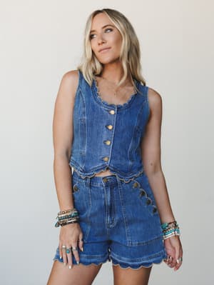 A denim two-piece set with serious personality — scalloped edges, gold button detail, and a full arm of turquoise and beaded bracelets that do exactly what they're supposed to do.