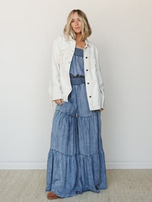 A breezy two-piece denim set — wide-leg tiered pants with a smocked waist paired with a matching strapless top — layered under a cream fringe jacket for a look that feels equal parts free-spirited and put-together.