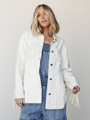 An oversized cream fringe jacket worn open over a blue denim smocked two-piece set — effortlessly western-boho with just enough personality to carry a whole outfit on its own.