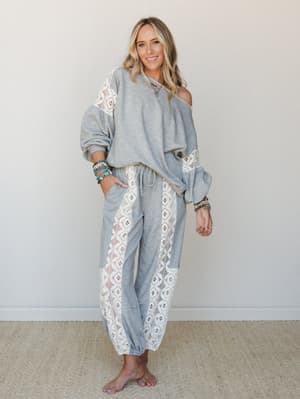A relaxed two-piece matching set in heathered grey with wide crochet lace panel inserts — worn off-shoulder and styled with turquoise jewelry and stacked bracelets for an effortlessly boho-comfortable feel.