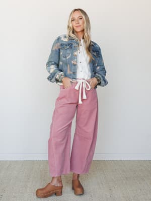 A relaxed, layered look built around wide-leg mauve corduroy pants, a white button-down tied at the waist, and a floral-printed denim jacket — styled with stacked bracelets and wooden clogs for that effortlessly personal, lived-in kind of cool.