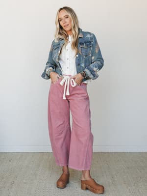 A relaxed, layered look built around wide-leg mauve corduroy pants styled with a white button-down and a floral-printed denim jacket — the kind of outfit that looks effortless but definitely wasn't an accident.