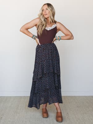 A polka dot tiered maxi skirt paired with a deep brown lace-trim cami creates that effortless mix of feminine and grounded — styled with tan clogs and stacked turquoise bracelets for a boho-casual look that feels both relaxed and intentional.