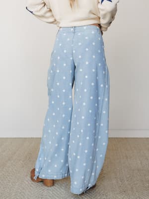 Shot from behind, this look pairs wide-leg light denim polka dot pants — with a sweet drawstring hem detail — against a cream knit sweater with navy star embroidery, giving it a playful, vintage-leaning feel.