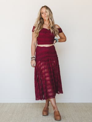 A rich burgundy lace two-piece set styled with wood clogs and stacked bracelets — the kind of outfit that feels equally at home at a wedding reception or a weekend farmers market with good lighting.
