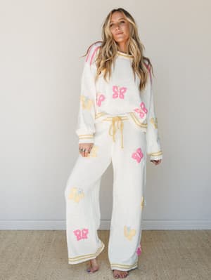 A cream knit matching set covered in playful multicolor butterfly appliqués — the kind of outfit that makes a Saturday morning feel like something worth getting dressed for.