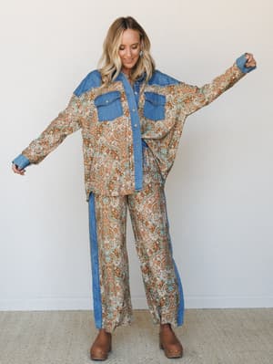 A matching paisley-and-denim two-piece set styled with easy confidence — the oversized button-down shirt and wide-leg pants share the same warm brown print with denim contrast paneling, giving the whole look a vintage western-meets-boho energy.