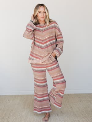 A matching striped waffle-knit two-piece set — relaxed pullover top and wide-leg flare pants — styled with stacked bracelets and a delicate necklace, shot against a clean white studio backdrop with an effortlessly lived-in feel.