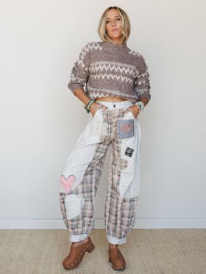 A model styled in a cropped Fair Isle sweater and patchwork wide-leg pants covered in heart appliqués — the kind of outfit that looks like it was pieced together from your favorite vintage finds and a lot of love.