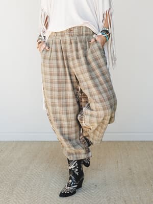A relaxed, lived-in plaid trouser styled with a fringe white top and embroidered black cowboy boots — the kind of outfit that looks effortless but clearly has a point of view.