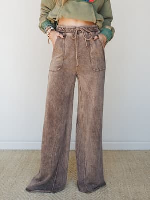 Mineral-washed wide-leg pants in a warm mocha tone, styled with a cropped sage hoodie and stacked bracelets — the kind of effortless, lived-in combo that feels equally at home on a coffee run or a lazy Sunday.