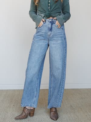 Wide-leg, high-rise jeans in a medium stone blue wash styled with a knotted green thermal top and leopard print booties — the kind of effortless denim outfit that looks like it took zero effort and exactly the right amount.
