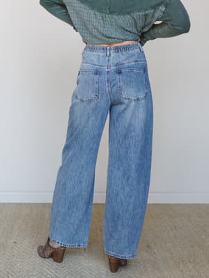 Shot from the back, a model pairs easy wide-leg jeans in a lived-in medium wash with a cropped sage green textured top and leopard print block heels — the kind of outfit that looks effortless but clearly wasn't accidental.