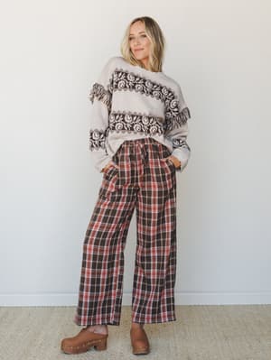 A relaxed fall outfit pairing wide-leg plaid pants with a Fair Isle-inspired fringe sweater and wood clogs — the kind of look that feels effortlessly put-together on a coffee run or a crisp weekend morning.