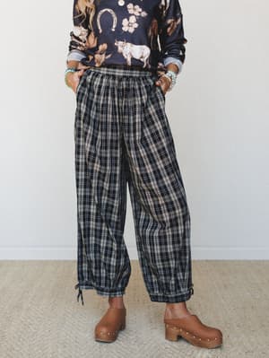 A relaxed plaid jogger in moody navy and taupe paired with a Western-graphic sweatshirt and wooden clogs — the kind of outfit that looks effortless but is clearly very on purpose.