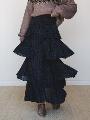 A dramatic tiered maxi skirt in deep navy-black velvet burnout fabric styled with a cozy fair isle sweater and leopard ankle boots — the kind of outfit that makes a Tuesday feel like something worth dressing for.