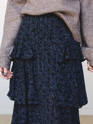 A close-up torso shot of a tiered velvet polka dot maxi skirt in deep navy paired with a chunky oatmeal knit sweater — moody, romantic, and the kind of outfit that makes a Tuesday feel like something.