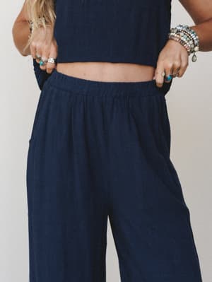 A close-cropped mid-shot of a navy wide-leg pant and matching cropped top set, styled with layered silver and turquoise jewelry for that effortless boho-everyday feel.