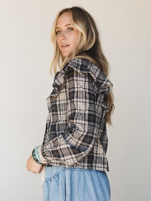 A model shot over the shoulder in a quilted plaid blouse layered over a soft blue skirt — the kind of outfit that feels like fall without trying too hard.
