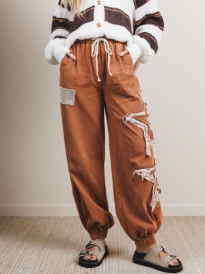 Person wearing brown distressed cargo pants with a white and brown sweater.