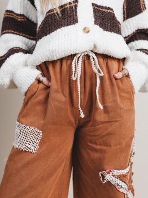 Brown pants with lace details worn with a striped sweater.