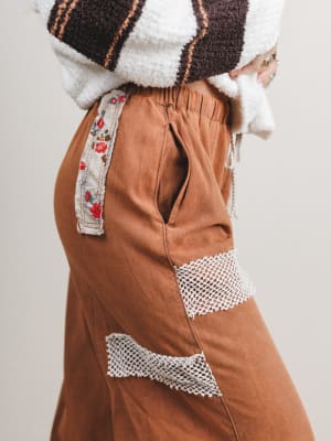 Brown pants with floral and geometric patterns on a plain background