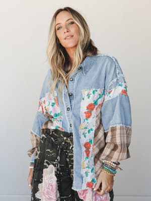 A patchwork denim shacket layered over a dark floral skirt — the kind of piece that looks like it was assembled from the best parts of a vintage quilt and your favorite worn-in denim shirt.
