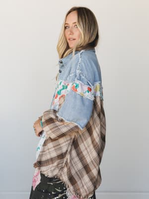 A patchwork shacket mixing light wash denim, floral fabric, and brown plaid panels with raw frayed edges — the kind of piece that looks like it's been collecting stories for years.