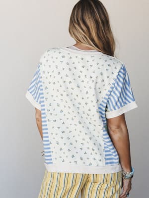 A back-view shot of a mixed-print top that pairs a ditsy floral center panel with blue-and-white stripes on the sleeves and sides — the kind of piece that looks like it was made from your favorite vintage scraps, in the best way.