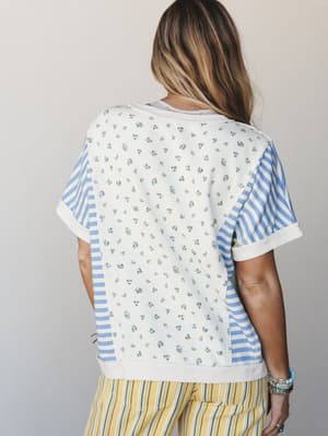 A back-view shot of a mixed-print top that pairs a ditsy floral center panel with blue-and-white stripes on the sleeves and sides — the kind of piece that looks like it was made from your favorite vintage scraps, in the best way.
