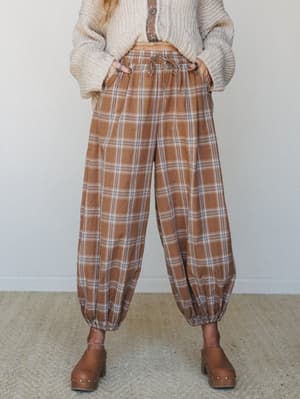 Relaxed plaid balloon pants in a warm latte brown paired with a chunky cream knit cardigan and wooden clogs — the kind of outfit that makes a coffee run feel like a whole moment.