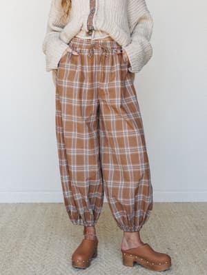 Plaid balloon pants in a warm latte brown are styled with a chunky cream knit cardigan and brown platform clogs — the kind of outfit that makes a cozy Saturday feel intentional.