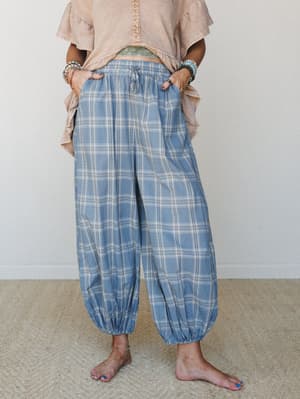 Plaid harem-style pants in a soft steel blue styled with a washed peach ruffle top, stacked bracelets, and bare feet — the kind of outfit that looks effortless but was definitely a whole mood.