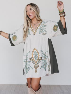 woman wearing caftan style dress in cream with print accents and gray trim