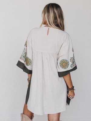Back view of woman wearing caftan style dress in cream with print accents and gray trim