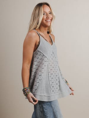 Woman wearing a light gray sleeveless top with a subtle pattern