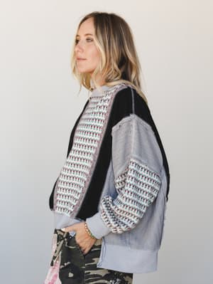 A side-profile shot of a model in a patchwork mixed-media bomber jacket layered over camo pants — the kind of outfit that looks thrown together in the best possible way.