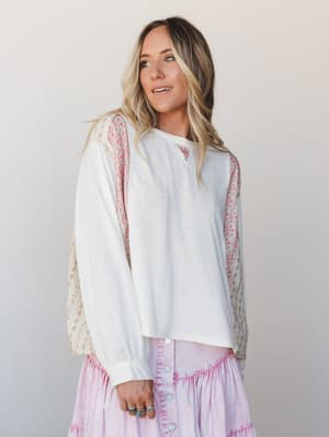 A relaxed long-sleeve top in cream jersey pairs floral print contrast panels along the sleeves and sides with a soft, worn-in feel — styled over a lavender button-front skirt for an effortlessly mixed-print moment.